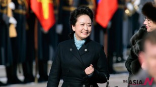 Chinese President Xi Jinping's wife Peng Liyuan smiles after arriving at the government airport Vnukovo II, outside Moscow, Russia. New Chinese first lady Peng is emerging as Chinese diplomacy's latest star. A well-known performer on state television, the glamorous Peng was featured prominently on Sunday's state media coverage of President Xi Jinping's activities in Russia. The visit is Xi's first since assuming the presidency earlier this month. (Photo : AP Photo/NEWSis/Ivan Sekretarev)