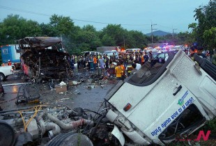 The charred wreckage of a double-decker passenger bus, top left, sits in the middle of a highway after a collision with a truck, foreground, in Saraburi province, northeast of Bangkok, Thailand Tuesday, July 23, 2013. The bus caught fire after the collision early Tuesday, killing 19 people and injuring 20 others, authorities said. (AP Photo) THAILAND OUT