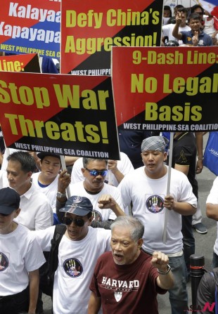 Former Philippine Senator and a human rights lawyer Rene Saguisag, front, clenches his fist while singing patriotic song during a rally at the Chinese Consulate at the financial district of Makati city, east of Manila, Philippines to protest alleged bullying by China in the current row over the Spratlys Group of islands in the South China Sea Wednesday July 24, 2013. The protesters, under the newly-formed West Philippine Sea Coalition (WSPC), urged the Chinese government to stop alleged intrusions into the West Philippine Sea and should act like a "good neighbor" to other countries in the region. (AP Photo/Bullit Marquez)