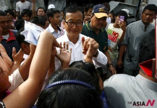 Sam Rainsy, center, President of Cambodia National Rescue Party (CNRP) greets villagers during a tour to visit polling station at Chak Angre Leu pagoda, in Phnom Penh, Cambodia, Sunday, July 28, 2013. Cambodians began voting across the country Sunday to take part in what has become a familiar ritual - the re-election of Prime Minister Hun Sen, who has been on the job for 28 years and says he hopes to rule for at least another decade. (AP Photo/Heng Sinith)