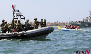 Tourists on a banana boat sail past an Indonesian navy speed boat with special force members onboard, during a security patrol for the upcoming Asia-Pacific Economic Cooperation (APEC) forum in Bali, Indonesia, Friday, Sept. 27, 2013. (NEWSis/AP)