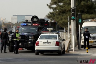 Two policewomen, right, a traffic police, in yellow vest, and members of a SWAT team guard a street corner, where, on Monday, a sport utility vehicle veered into a crowd near Tiananmen Gate, where the car crashed and caught fire, in Beijing, China, Wednesday, Oct. 30, 2013. Chinese police are circulating a list of eight suspects wanted in connection with the apparent suicide car crash near Tiananmen Square in Beijing that killed five people and injured dozens, a hotel manager said Wednesday. (AP/NEWSis)