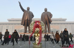 North Koreans visit Mansu Hill to pay their respects at the base of statues of the late leaders Kim Il Sung, left, and Kim Jong Il in Pyongyang, North Korea, Tuesday, Dec. 17, 2013, on the second anniversary of the death of Kim Jong Il. (AP/NEWSis)