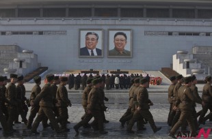 North Koreans soldiers march on Kim Il Sung Square in Pyongyang as others pay their respects beneath portraits of the late leaders Kim Jong Il, right, and Kim Il Sung on Tuesday, Dec. 17, 2013. North Koreans observed the second anniversary of the death of Kim Jong Il. (AP/NEWSis)