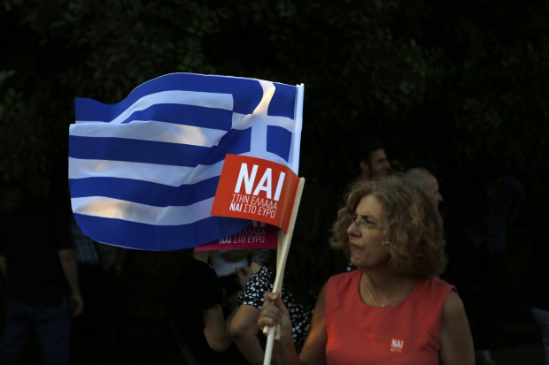 A demonstrator holds a Greek flag and another one reading ''Yes'' during a rally organized by supporters of the Yes vote in Athens, Friday, July 3, 2015. A new opinion poll shows a dead heat in Greece's referendum campaign with just two days to go before Sunday's vote on whether Greeks should accept more austerity in return for bailout loans. (AP Photo)