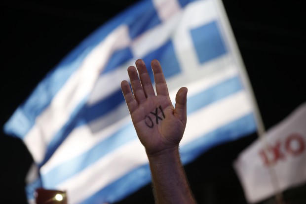 A demonstrator rises his hand reading the word ''No'' as a Greek flag waves during a rally organized by supporters of the No vote in Athens, Friday, July 3, 2015. A new opinion poll shows a dead heat in Greece's referendum campaign with just two days to go before Sunday's vote on whether Greeks should accept more austerity in return for bailout loans. (AP Photo)