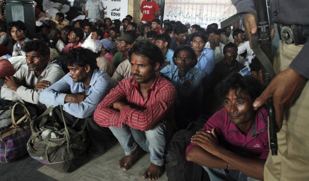 A Pakistani police officer stands guard as Indian fishermen wait for train to leave for India after their release from the central jail in Karachi, Pakistan, Sunday, Aug. 2, 2015. Some 163 Indian fishermen left for home after they were released from detention in Pakistan for alleged illegal entry and fishing in Pakistani waters in the Arabian Sea, an official said. (AP Photo/Fareed Khan)