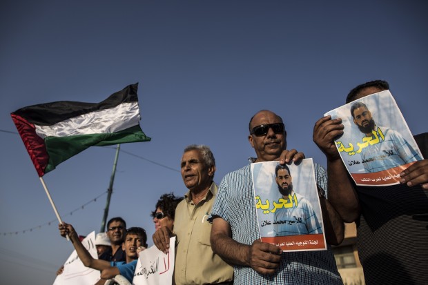 Arab protesters wave a Palestinian flag and hold posters of Mohammed Allan, a Palestinian prisoner who is on a long-term hunger strike, during a rally calling for his release in Rahat, southern Israel. (Xinhua) 