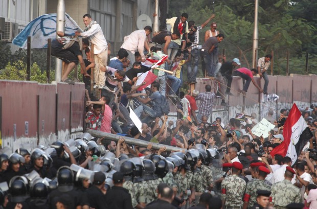 Egyptian military and policemen stand by the Israeli Embassy in Cairo, Egypt, as hundreds of protesters demolish part of the concrete wall built to protect the embassy from demonstrators. Israel has reopened its embassy in Cairo, four years after an Egyptian mob ransacked the site where the mission was previously located. The Israeli flag was raised during its opening ceremony at the new location of the embassy on Wednesday, Sept. 9, 2015. (AP Photo/Amr Nabil, File) 