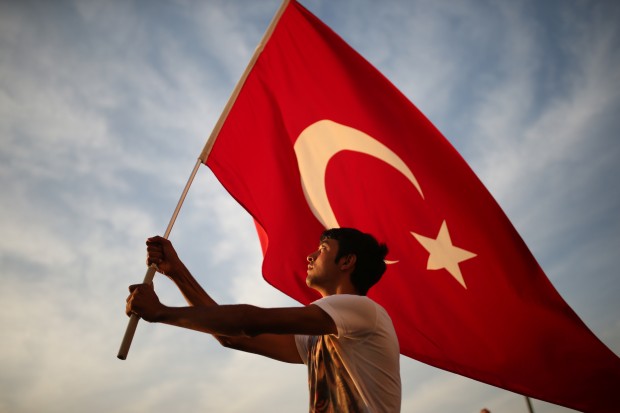 A man waves a national flag as thousands of people march to protest against the deadly attacks on Turkish troops, in Izmir, Turkey. (AP Photo/Emre Tazegul) 