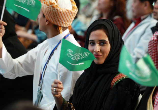 A woman waves the national flag of Saudi Arabia at a ceremony marking the National Pavilion Day for Saudi Arabia. (Xinhua/Ren Long)