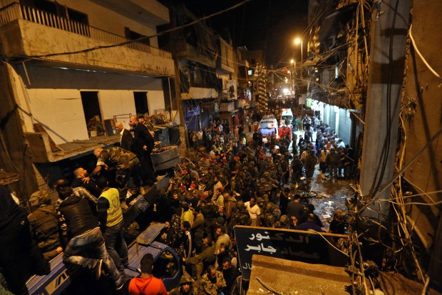 Lebanese army and civilians gather near the site of a twin suicide attack in Burj al-Barajneh, southern Beirut, Lebanon, Thursday, Nov. 12, 2015 that struck a Shiite suburb killed and wounded dozens, according to a Lebanese official. (AP Photo/Bilal Hussein) 