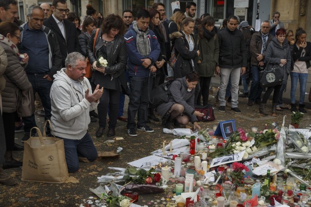 A Muslim, left, prays in front of a floral tributes near the Bataclan concert hall after the terror attacks in Paris, Monday, Nov. 16, 2015. France is urging its European partners to move swiftly to boost intelligence sharing, fight arms trafficking and terror financing, and strengthen border security in the wake of the Paris attacks. (AP Photo/Daniel Ochoa de Olza)