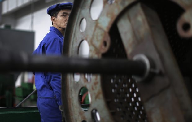 In this May 6, 2016 file photo, a North Korean worker looks from behind a piece of machinery at the Pyongyang 326 Electric Wire Factory, seen during a press tour, in Pyongyang, North Korea.  North Korea remains one of the world’s least developed economies. Stunting due to malnutrition, abject poverty and the lack of economic options surely persist. But no more so than in many other poor nations. (AP Photo/Wong Maye-E)