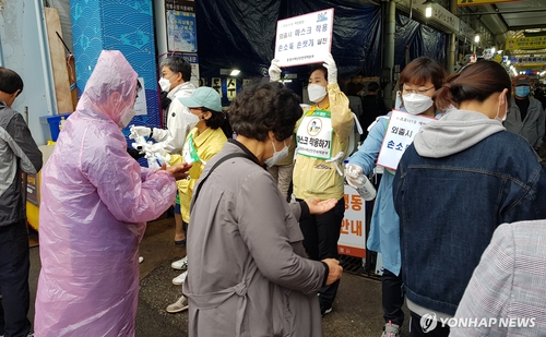 This photo provided by the city of Tongyeong shows local officials and volunteers holding a hand sanitation campaign at a market in the southwestern coastal city on May 3, 2020. (Yonhap)