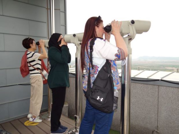 Ghena and Lama looking at the North Korean territory through binoculars from the observatory in South Korea