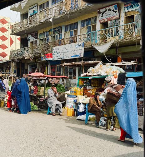 In Afghanistan, it is taboo for men to look directly at women. In the photo, the male merchant covered his eyes with the palm of his hand as a woman wearing a burka passed by.